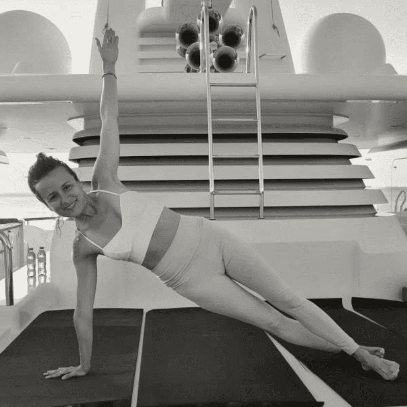 A private yoga instructor guiding a morning vinyasa flow on a yacht sundeck