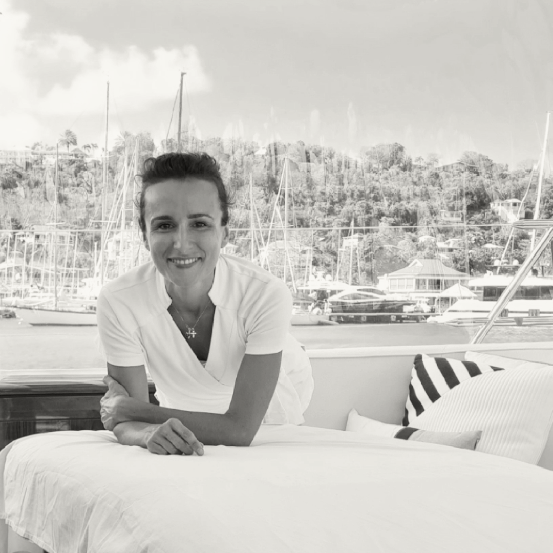 A wellness professional leading a private sunrise yoga session on a superyacht